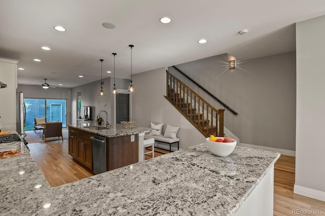 kitchen with light stone counters, light hardwood / wood-style floors, sink, and hanging light fixtures