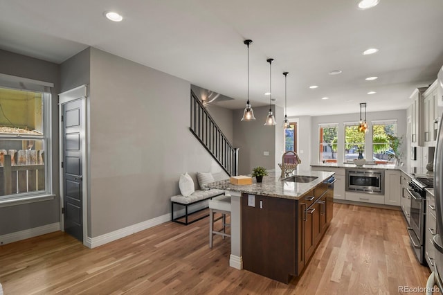 kitchen featuring sink, white cabinetry, hanging light fixtures, a kitchen breakfast bar, and a center island with sink