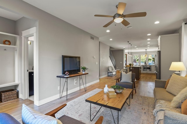 living room with sink, ceiling fan, and light hardwood / wood-style flooring