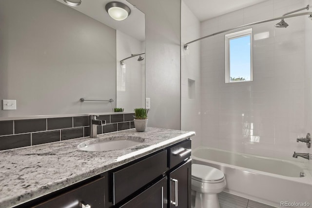 full bathroom featuring vanity, decorative backsplash, tile patterned floors, toilet, and tiled shower / bath