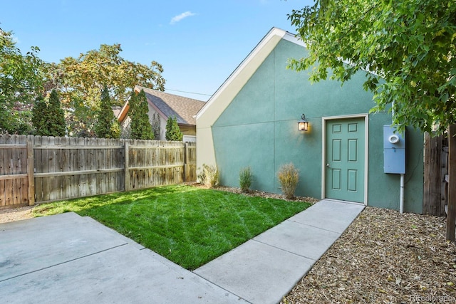 view of exterior entry featuring a yard and a patio area