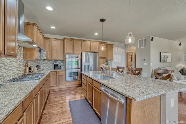 15235 W Iliff Ave, Lakewood, CO 80228 - kitchen with appliances with stainless steel finishes, a sink, open floor plan, a center island with sink, and light stone countertops