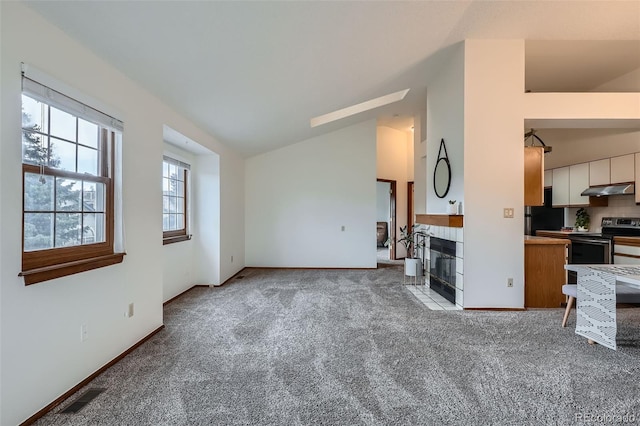 1661 S Fulton St, Aurora, CO 80247 - unfurnished living room with carpet flooring, baseboards, a tiled fireplace, and high vaulted ceiling