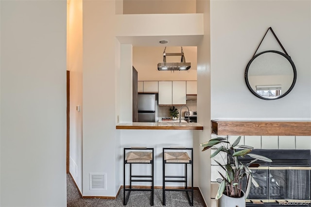 1661 S Fulton St, Aurora, CO 80247 - kitchen with freestanding refrigerator, backsplash, carpet flooring, and a kitchen bar
