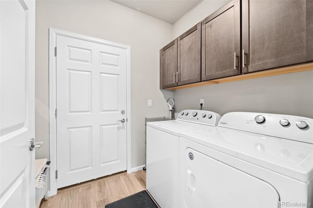 clothes washing area with independent washer and dryer, cabinets, and light wood-type flooring