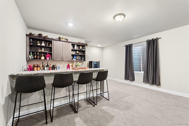 bar featuring tasteful backsplash, light colored carpet, and light stone countertops