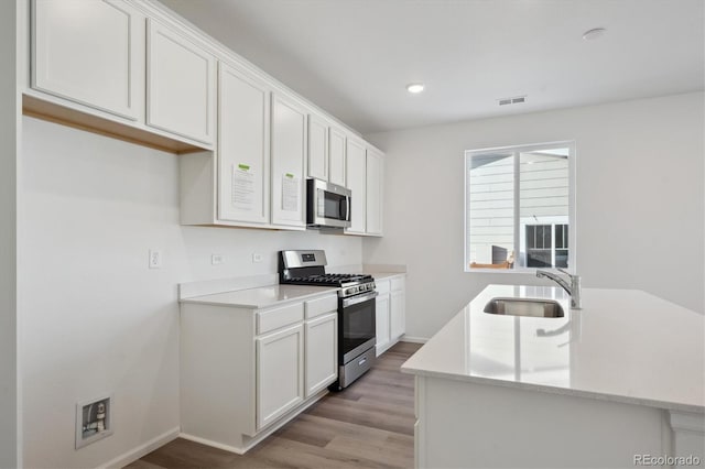 kitchen featuring white cabinets, light wood-type flooring, stainless steel appliances, and sink