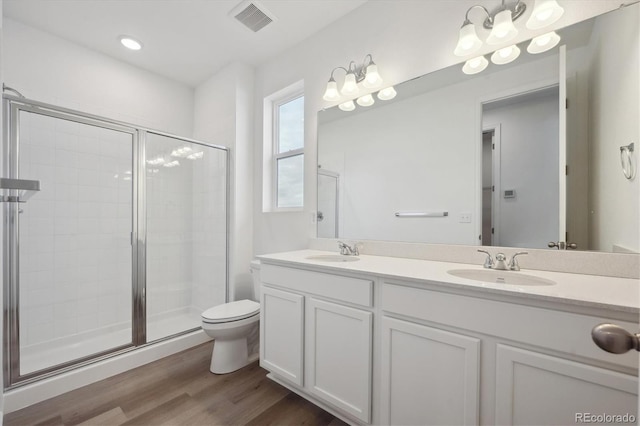 bathroom with wood-type flooring, vanity, toilet, and a shower with shower door