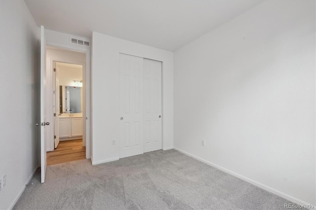 unfurnished bedroom with light carpet and a closet