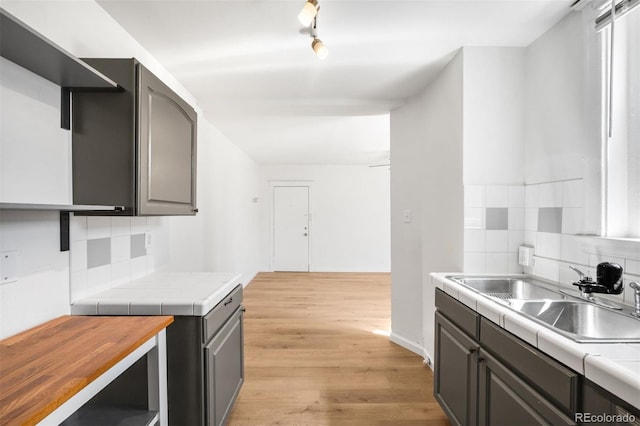 215 E 11th Ave Unit D5, Denver, CO 80203 - kitchen with tile counters, a sink, light wood-type flooring, backsplash, and gray cabinetry
