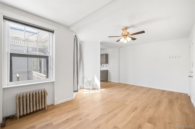 215 E 11th Ave Unit D5, Denver, CO 80203 - unfurnished living room with radiator, light wood-style floors, ceiling fan, and baseboards