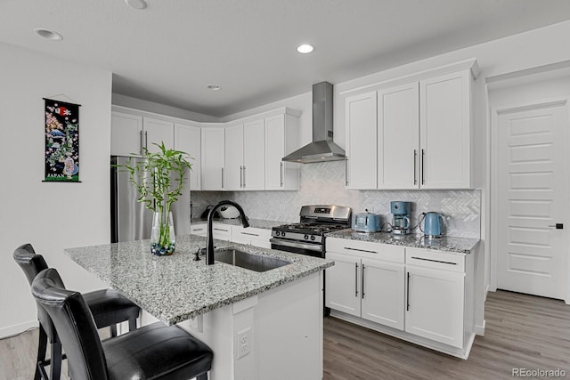 20999 E Quincy Dr, Aurora, CO 80015 - kitchen with stainless steel range with gas cooktop, wall chimney exhaust hood, a sink, light stone countertops, and wood finished floors