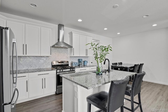 20999 E Quincy Dr, Aurora, CO 80015 - kitchen featuring appliances with stainless steel finishes, wall chimney exhaust hood, a sink, light stone counters, and white cabinets
