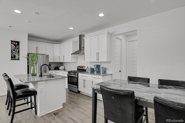 20999 E Quincy Dr, Aurora, CO 80015 - kitchen with appliances with stainless steel finishes, wall chimney exhaust hood, a breakfast bar area, light stone countertops, and white cabinets