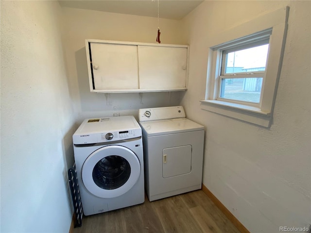 laundry room featuring washer and clothes dryer, cabinets, and hardwood / wood-style floors