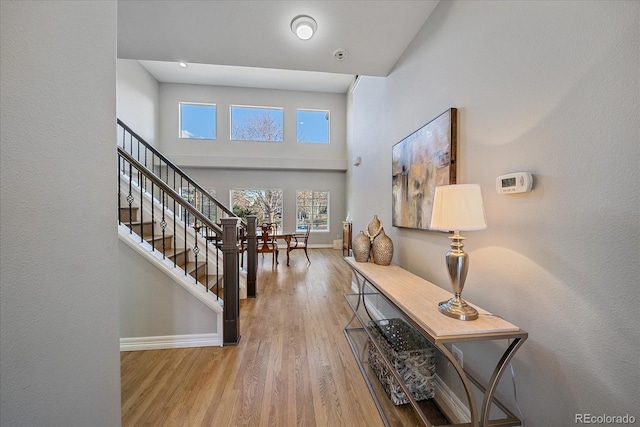 entrance foyer with stairs, a high ceiling, wood finished floors, and baseboards