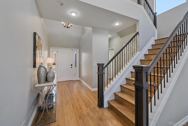 foyer featuring a high ceiling, stairway, baseboards, and wood finished floors