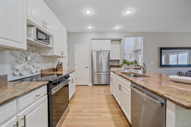 kitchen featuring stainless steel appliances, light wood-style floors, white cabinetry, and a sink