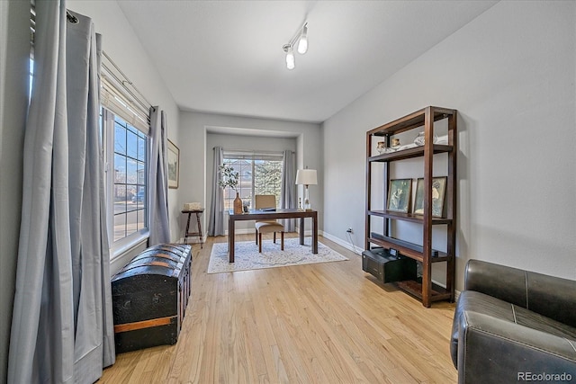 home office with rail lighting, light wood-style flooring, and baseboards