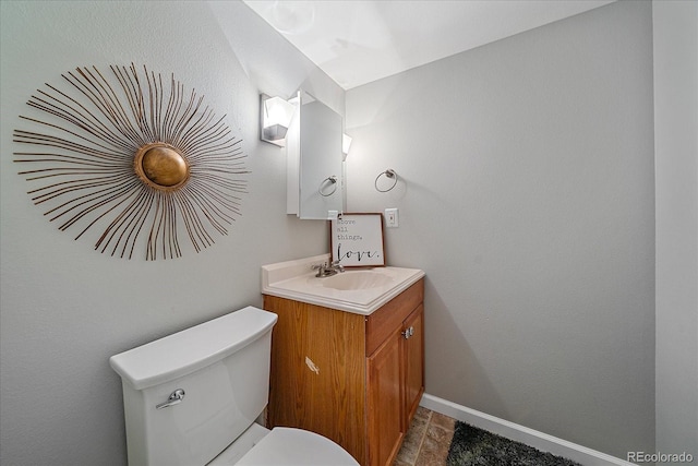 half bath with toilet, baseboards, and vanity