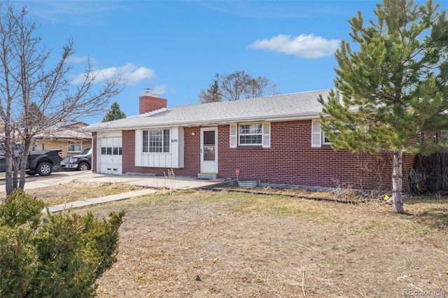 single story home featuring concrete driveway, a chimney, roof with shingles, an attached garage, and brick siding