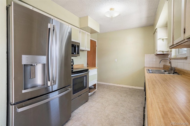 kitchen featuring stainless steel appliances, light countertops, a sink, and decorative backsplash