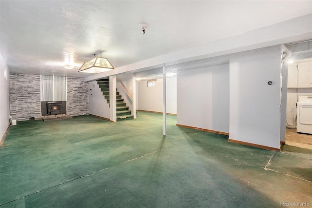 finished basement featuring a wood stove, washer / dryer, baseboards, and stairway