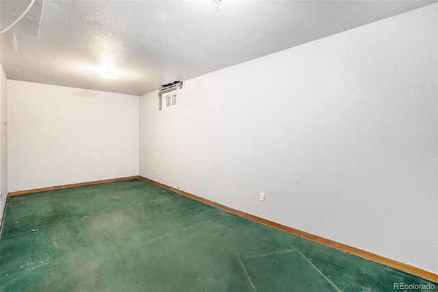 carpeted empty room featuring a textured ceiling and baseboards