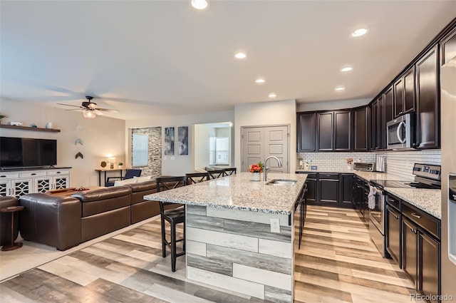 6883 E 132nd Pl, Thornton, CO 80602 - kitchen with stainless steel appliances, a kitchen bar, light stone countertops, open floor plan, and recessed lighting