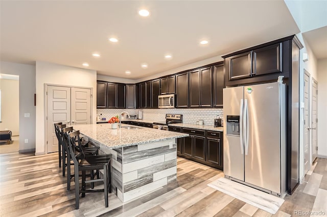 6883 E 132nd Pl, Thornton, CO 80602 - kitchen with appliances with stainless steel finishes, light stone counters, decorative backsplash, light wood-style flooring, and recessed lighting