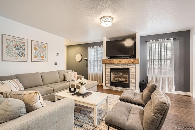 living room with a textured ceiling, a fireplace, baseboards, and wood finished floors