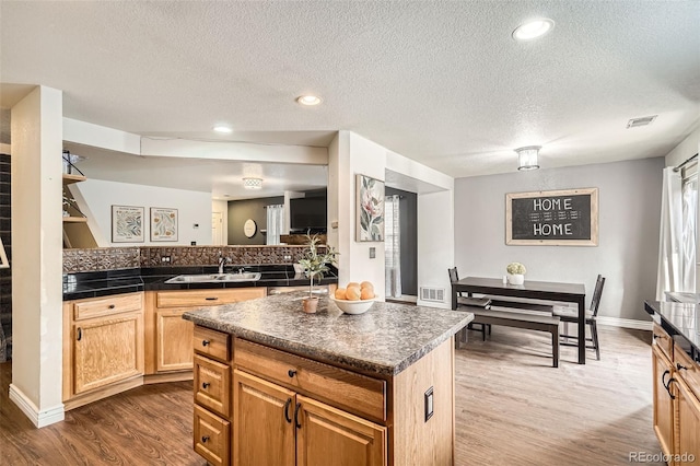 kitchen featuring dark wood-style floors, dark countertops, visible vents, and a sink