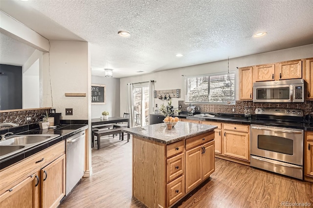 kitchen featuring dark countertops, light wood finished floors, a kitchen island, and stainless steel appliances