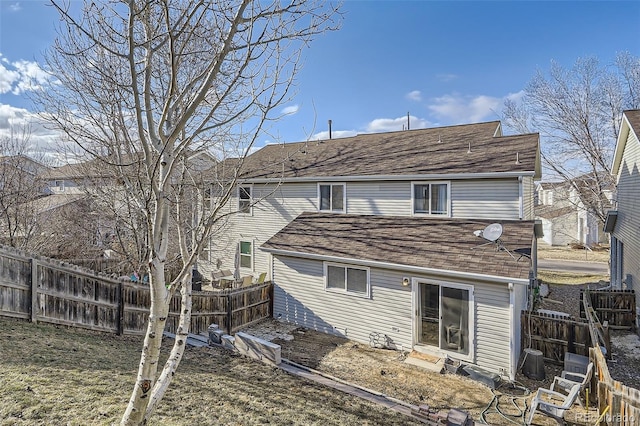 rear view of property with a shingled roof and fence