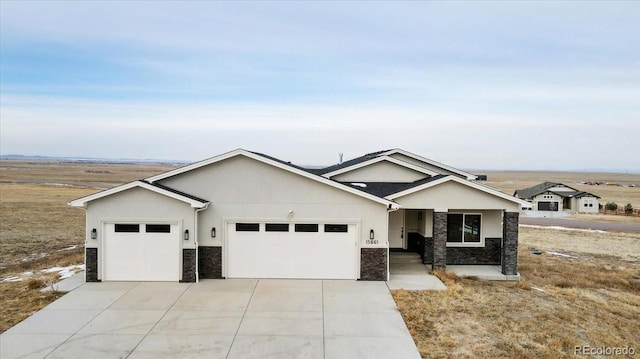 ranch-style house featuring stone siding, concrete driveway, an attached garage, and stucco siding