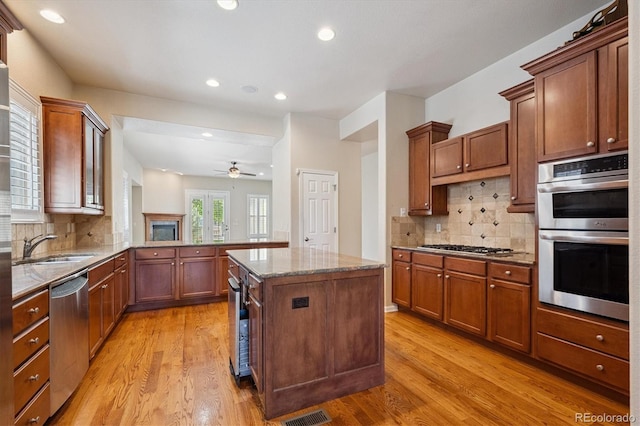 10205 Bluffmont Dr, Lone Tree, CO 80124 - kitchen with stainless steel appliances, light stone countertops, light wood-type flooring, a ceiling fan, and recessed lighting