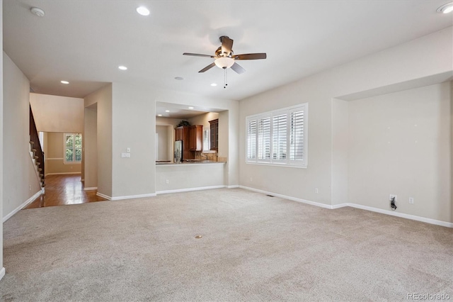 10205 Bluffmont Dr, Lone Tree, CO 80124 - unfurnished living room featuring light carpet, ceiling fan, stairs, plenty of natural light, and recessed lighting