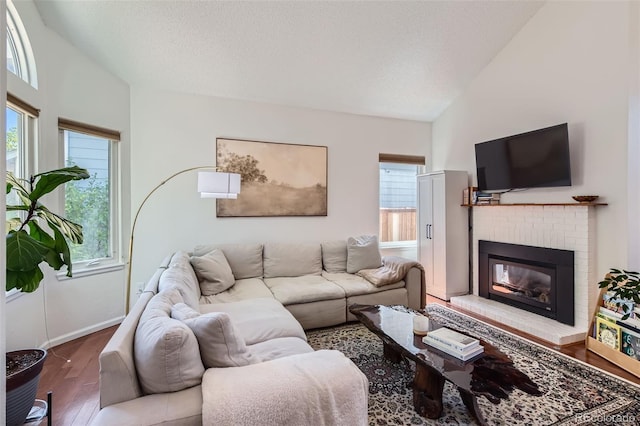 728 Poppywood Pl, Highlands Ranch, CO 80126 - living area with wood finished floors, a fireplace, vaulted ceiling, baseboards, and a textured ceiling