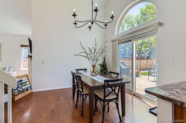 728 Poppywood Pl, Highlands Ranch, CO 80126 - dining space with hardwood / wood-style flooring, a chandelier, baseboards, and a towering ceiling