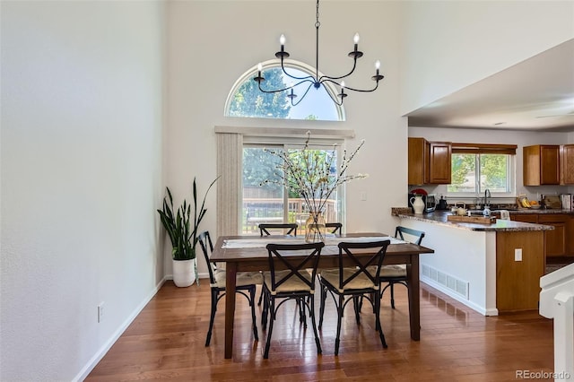 728 Poppywood Pl, Highlands Ranch, CO 80126 - dining space with a chandelier, dark wood finished floors, a towering ceiling, and baseboards