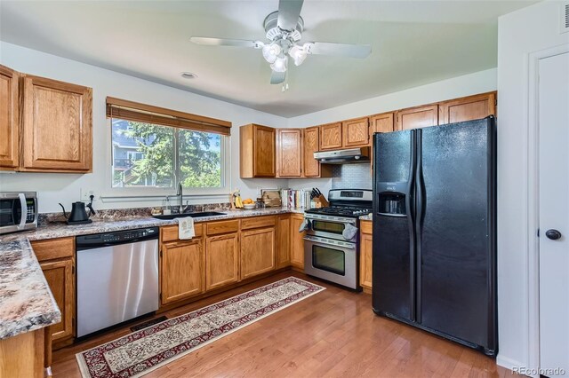 728 Poppywood Pl, Highlands Ranch, CO 80126 - kitchen featuring stainless steel appliances, under cabinet range hood, a sink, light wood-type flooring, and brown cabinets