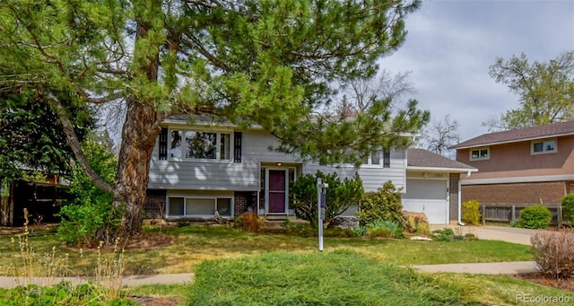 split foyer home featuring concrete driveway, a front lawn, brick siding, and a garage