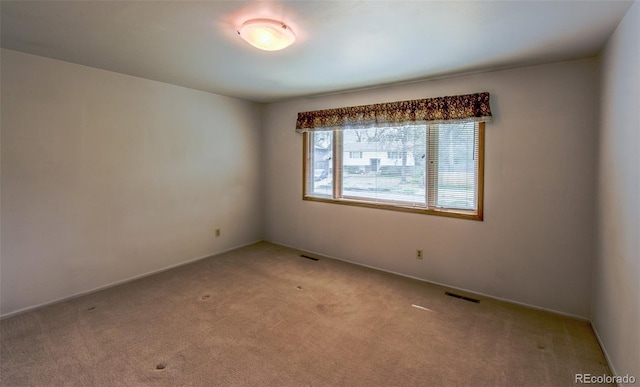 empty room featuring baseboards, visible vents, and light colored carpet