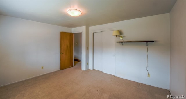 unfurnished bedroom with a closet and light colored carpet