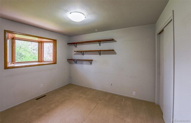 unfurnished bedroom with light carpet, visible vents, and a closet