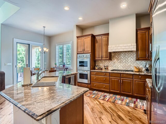 5092 S Allison Way, Littleton, CO 80123 - kitchen with stainless steel appliances, light wood-style flooring, backsplash, a chandelier, and light stone counters