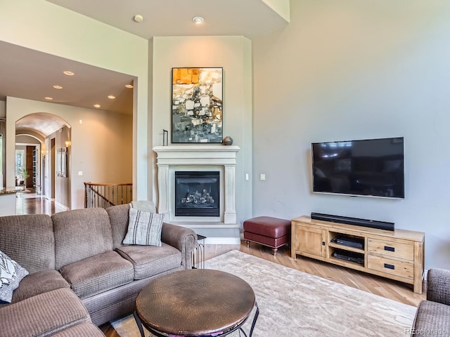 5092 S Allison Way, Littleton, CO 80123 - living area with arched walkways, wood finished floors, a glass covered fireplace, and recessed lighting