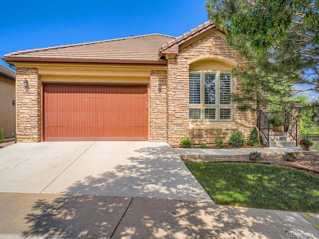 5092 S Allison Way, Littleton, CO 80123 - view of front of house with stone siding, driveway, an attached garage, and a tiled roof
