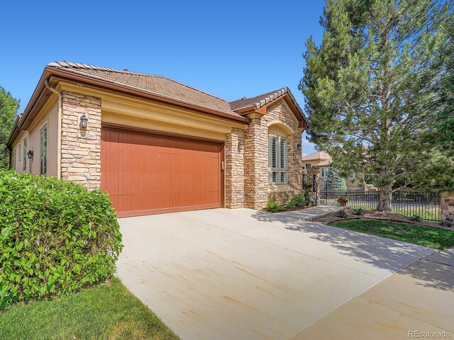 5092 S Allison Way, Littleton, CO 80123 - view of front facade with stone siding, an attached garage, concrete driveway, and a tiled roof