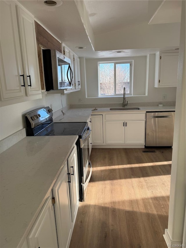 kitchen featuring sink, light hardwood / wood-style floors, white cabinets, and appliances with stainless steel finishes